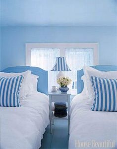 two beds in a room with blue walls and white bedding