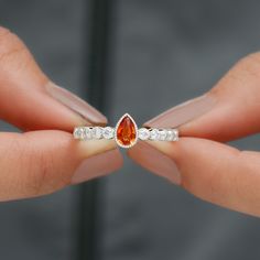 a woman's hand holding an orange and white diamond ring