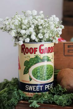 a tin can with flowers in it sitting on top of a table next to other items