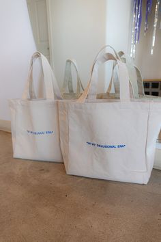 We are in our delusional era living our best life! 100% Cotton/ Blue embroidery Embroidered with love by JZD in Brownsville, TX Inside pocket Measurements Tote bag: 14" x 14" Depth: 5.5" Handles: 11" Custom Tote Bag Aesthetic, Aesthetic Totes, Canvas Tote Bag Design, Tote Bag Design Ideas, Business Merchandise, Business Merch, Tote Bag Business, Swag Bags, Branded Tote Bags