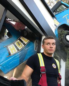 a man standing in front of a blue car