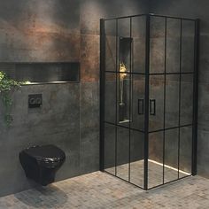 a black toilet sitting next to a walk in shower