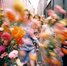 people are walking down the street with flowers in front of them