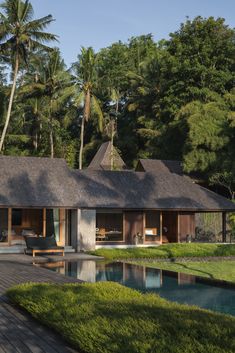 the house is surrounded by lush green trees and has a pool in front of it