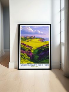 a framed poster on the floor in front of a window with an image of a golf course