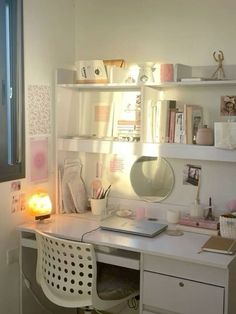 a white desk topped with a laptop computer next to a mirror and shelf filled with books