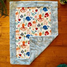 a baby blanket with an octopus and sea animals on it sitting on a wooden floor