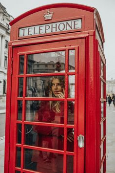 a red phone booth with a woman in it