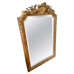 an ornate gold framed mirror with flowers and leaves on the top, against a white background