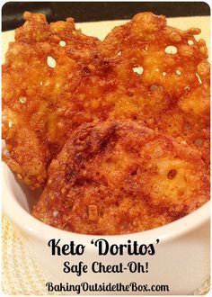 some fried food in a white bowl on a yellow table cloth with the words keto doritos safe cheesy