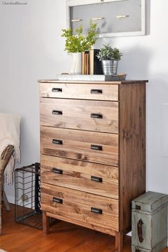 a wooden dresser sitting on top of a hard wood floor next to a white wall