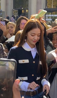 a woman is standing in front of a crowd with her cell phone up to her ear