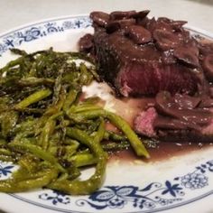 a blue and white plate topped with meat and green beans