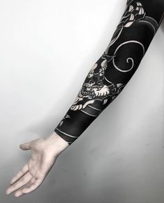 a person with a black and white tattoo on their arm is reaching out towards the camera