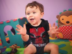 a little boy sitting on the floor with his hands out