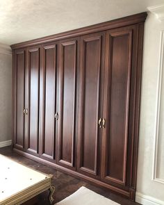 an empty room with large wooden cabinets in the corner and a bed on the other side