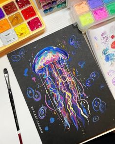 an art project with watercolors and paints on the table next to it is a drawing of a jellyfish