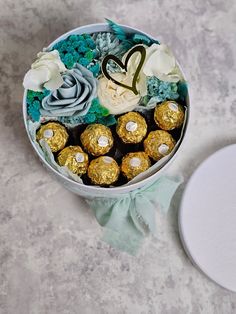 a white box filled with chocolates and flowers on top of a table next to a plate