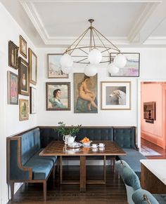 a dining room table with blue chairs and pictures on the wall