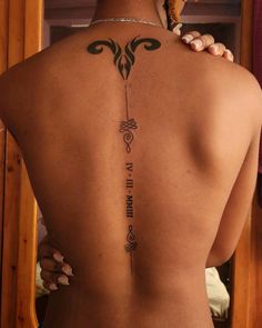 the back of a woman's body with tattoos on her upper and lower back