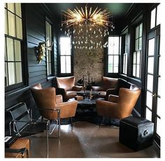 a living room filled with lots of furniture next to windows and a chandelier