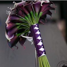 a purple and white flower arrangement in a glass vase on a wooden table with the stems still attached