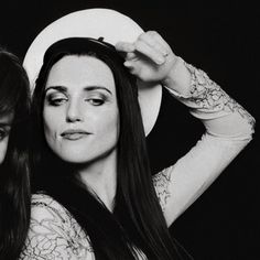 black and white photograph of two women with long hair, one holding her head in the other's hand