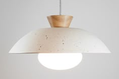 a white light hanging from a ceiling with a wooden cone on it's end