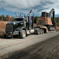 a tractor trailer hauling a large load down a dirt road