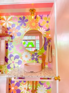 a bathroom with colorful flowers painted on the wall and vanity mirror above it, along with other accessories