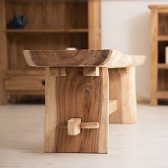 a wooden table sitting on top of a white floor next to a book shelf filled with books