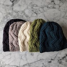 four knitted hats sitting on top of a marble counter