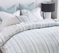 a bed with blue and white striped comforter next to a lamp on a nightstand