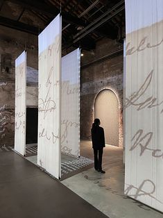 a man standing in front of some white walls with writing on it and an open doorway