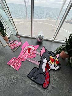 a cat rug and mirror on the floor next to some potted plants in front of an ocean view