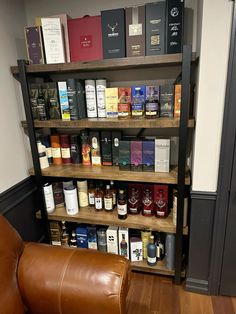 a leather chair sitting in front of a book shelf filled with books and liquor bottles