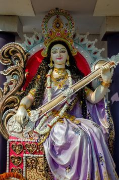 a statue of the hindu god person sitting on a throne with a long stick in his hand