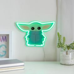 a baby yoda neon sign sitting on top of a desk