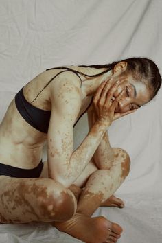 a woman covered in mud sitting on the ground with her hands to her face and eyes closed