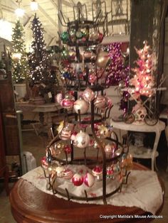 a christmas tree made out of ornaments in a room filled with other holiday trees and decorations