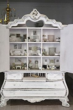 an old white china cabinet with many items on it