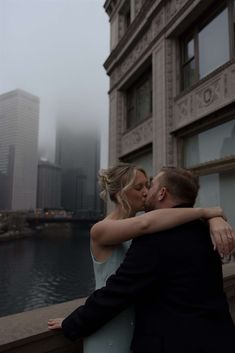 a bride and groom kissing in front of the chicago river