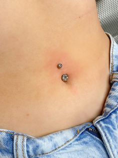 a woman's stomach with two piercings attached to the back of her belly