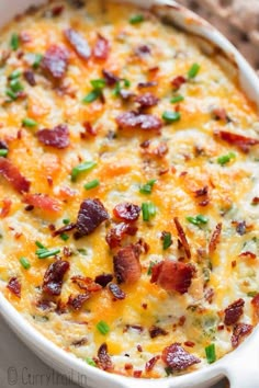 a casserole dish with bacon, cheese and green onions