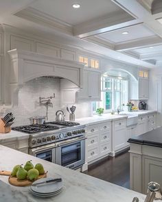 a large kitchen with white cabinets and marble counter tops