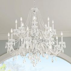 a chandelier hanging from the ceiling in a room with white walls and windows