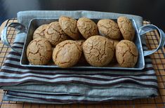 a metal tray filled with cookies on top of a wooden table next to a blue and white towel