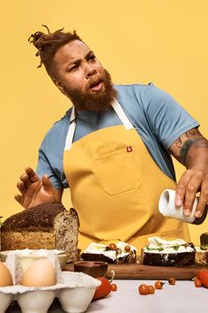 a man in an apron is preparing food on a table with bread, eggs and other items