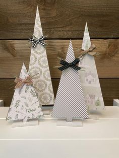 three small christmas trees are sitting on a white shelf with ribbon tied around the top