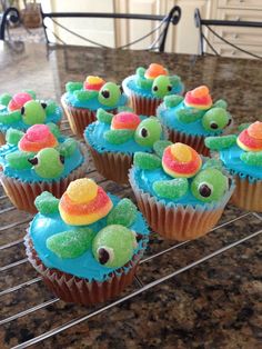 cupcakes with blue frosting and gummy bears on them sitting on a cooling rack